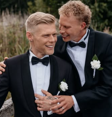 Aki Samuli eli Aki Kirvesniemi ja puoliso Niko poseeraavat mustissa smokeissa hääpäivänään elokuussa 2026.